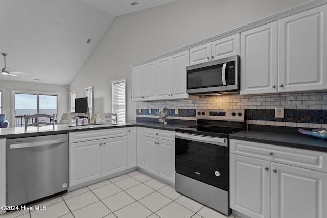 kitchen featuring dark countertops, appliances with stainless steel finishes, lofted ceiling, and a sink