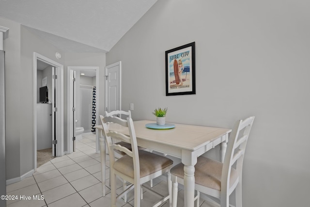 dining area featuring light tile patterned floors and lofted ceiling