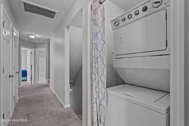 laundry area featuring visible vents, carpet flooring, laundry area, stacked washer and clothes dryer, and a textured ceiling