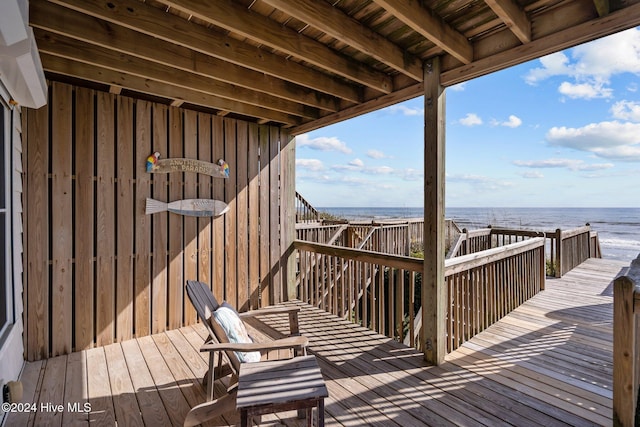 wooden deck featuring a water view and a beach view