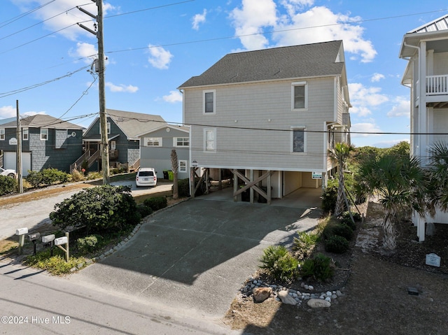 rear view of house featuring concrete driveway, a carport, and a residential view