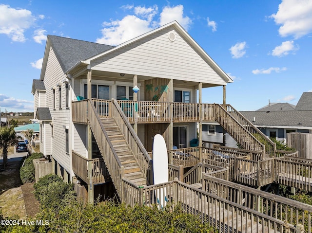 exterior space with a deck, stairway, and a shingled roof