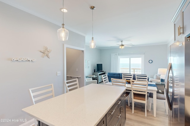 kitchen with light hardwood / wood-style floors, ceiling fan, a kitchen island, stainless steel refrigerator, and pendant lighting