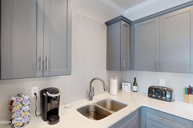 kitchen with tasteful backsplash, gray cabinetry, sink, and light stone counters