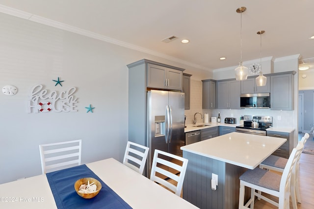 kitchen featuring hanging light fixtures, sink, a breakfast bar area, backsplash, and appliances with stainless steel finishes