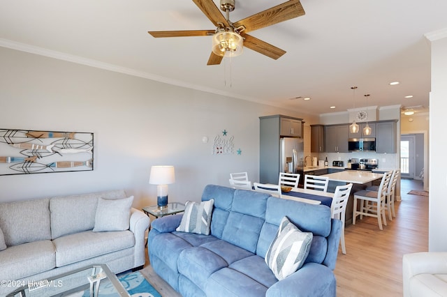 living room featuring light wood-type flooring, sink, ceiling fan, and ornamental molding