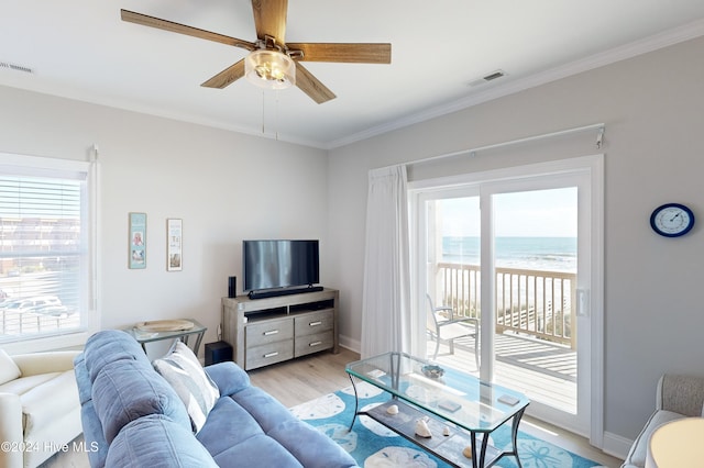 living room with a wealth of natural light, ceiling fan, light hardwood / wood-style floors, and ornamental molding