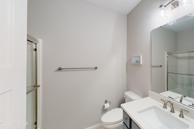 bathroom with toilet, vanity, and a shower with shower door