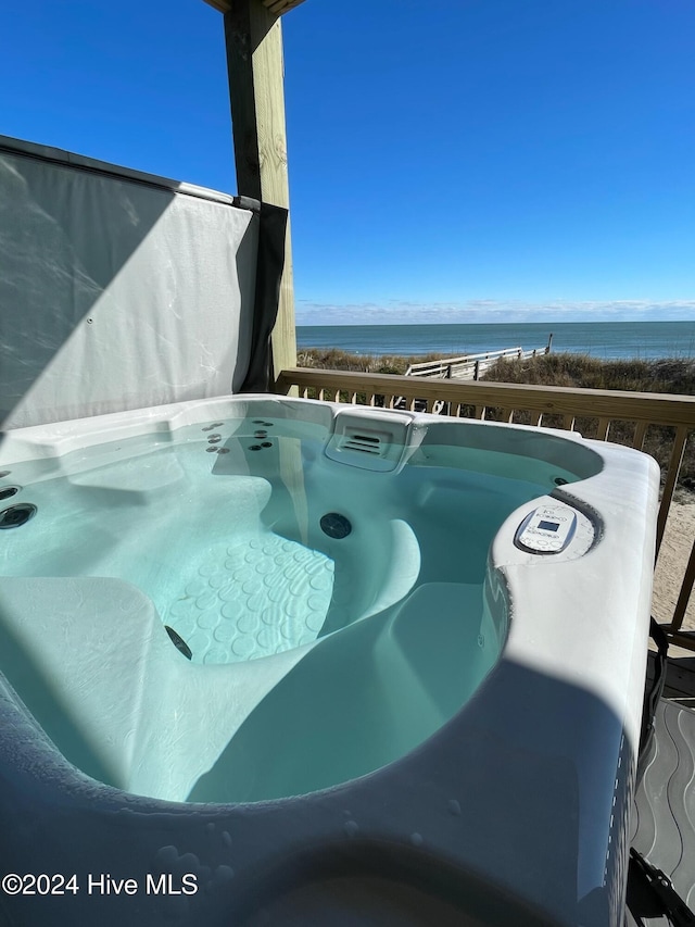 view of pool with a water view and a hot tub