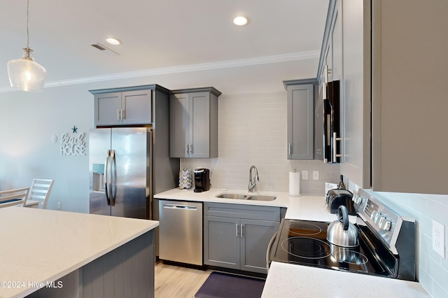 kitchen with crown molding, light wood-type flooring, appliances with stainless steel finishes, pendant lighting, and sink