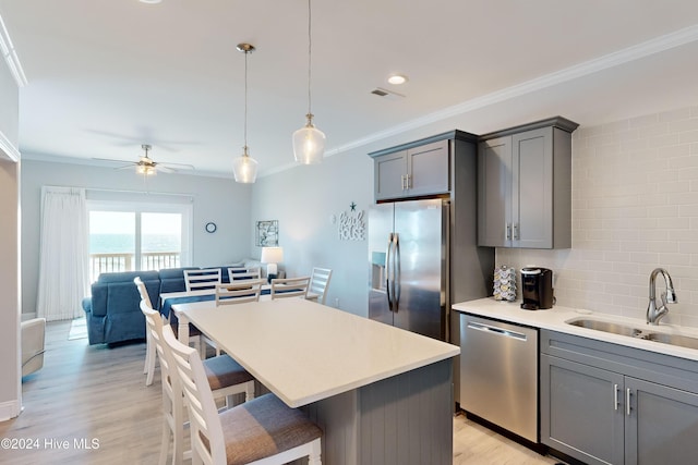 1796 New River Inlet Rd, North Topsail Beach, NC 28460 - kitchen with appliances with stainless steel finishes, a sink, gray cabinets, a breakfast bar, and ornamental molding