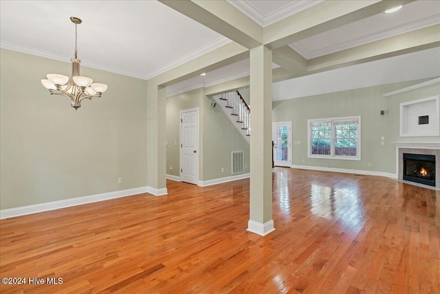 unfurnished living room featuring light wood-type flooring, a notable chandelier, beamed ceiling, and crown molding