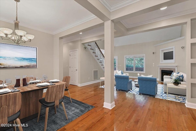 dining space featuring hardwood / wood-style floors, a tiled fireplace, beam ceiling, and crown molding