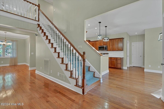 stairs featuring wood-type flooring and a chandelier