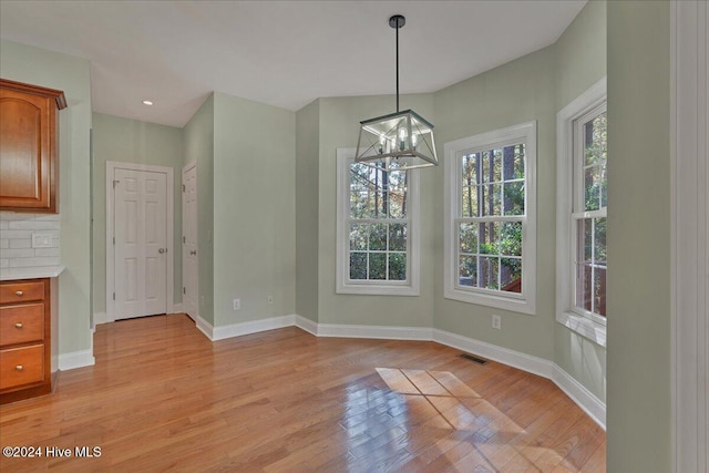 unfurnished dining area with a chandelier and light wood-type flooring