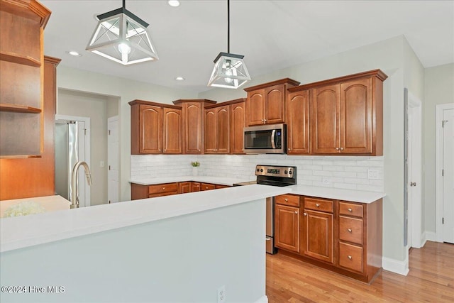 kitchen featuring stainless steel appliances, sink, tasteful backsplash, hanging light fixtures, and light hardwood / wood-style flooring