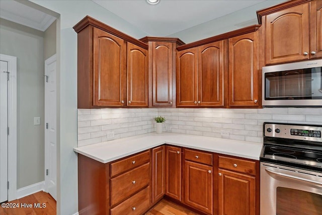 kitchen featuring light hardwood / wood-style flooring, tasteful backsplash, crown molding, and stainless steel appliances