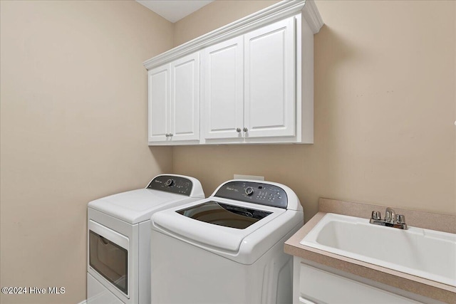 clothes washing area with cabinets, washing machine and dryer, and sink