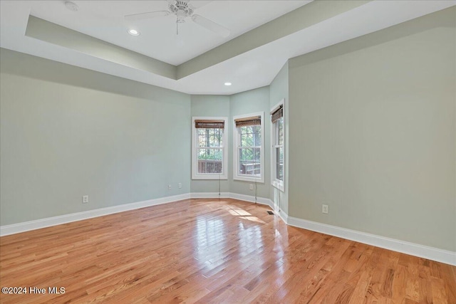 spare room featuring ceiling fan, light hardwood / wood-style floors, and a raised ceiling