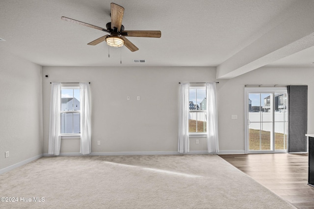 empty room featuring hardwood / wood-style floors, a textured ceiling, a wealth of natural light, and ceiling fan