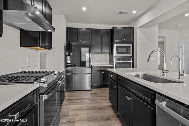 kitchen featuring sink, appliances with stainless steel finishes, light wood-type flooring, and light stone counters