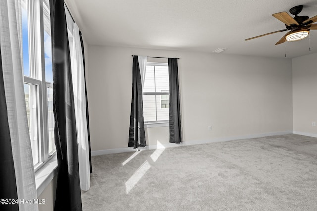 carpeted spare room featuring a textured ceiling and ceiling fan