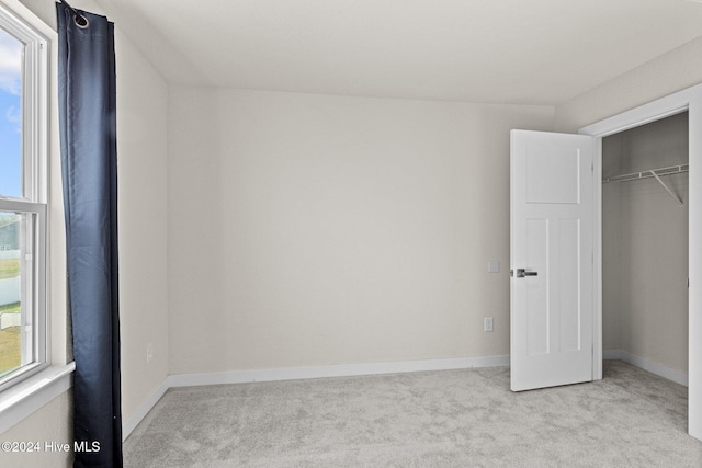 unfurnished bedroom featuring a closet and light colored carpet