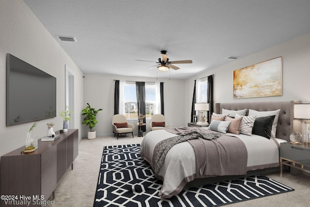 bedroom featuring ceiling fan, light colored carpet, and a textured ceiling