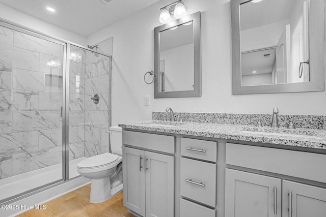 bathroom with wood-type flooring, toilet, an enclosed shower, and vanity