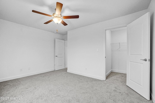 unfurnished bedroom with a spacious closet, light carpet, ceiling fan, and a closet