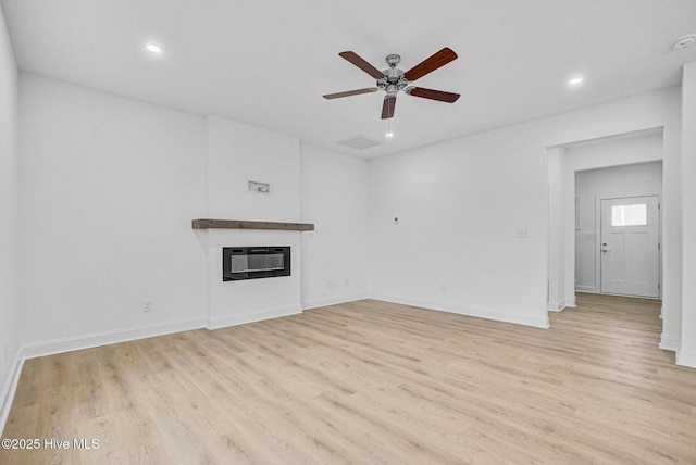 unfurnished living room with heating unit, light hardwood / wood-style floors, and ceiling fan