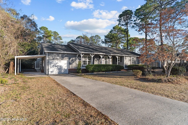 ranch-style house featuring brick siding, an attached carport, a front yard, a garage, and driveway