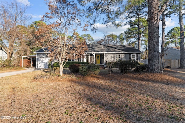 ranch-style house featuring an attached carport, fence, and driveway