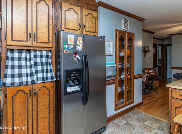 kitchen with stainless steel refrigerator with ice dispenser, crown molding, a textured ceiling, and light hardwood / wood-style floors