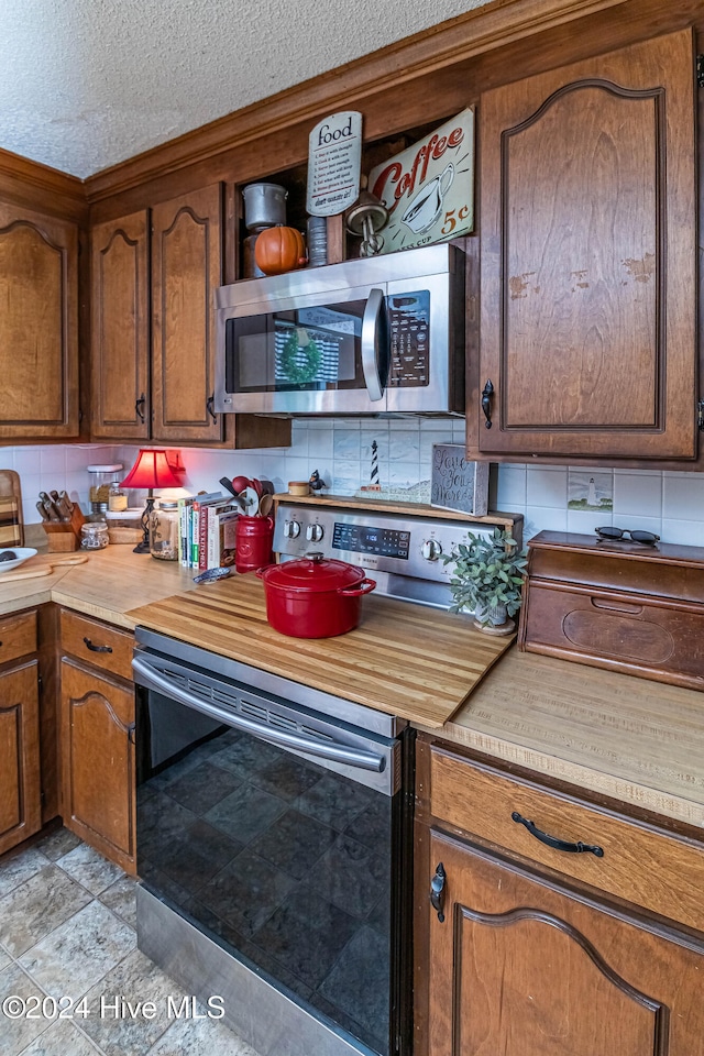 kitchen featuring stainless steel appliances, a textured ceiling, and decorative backsplash