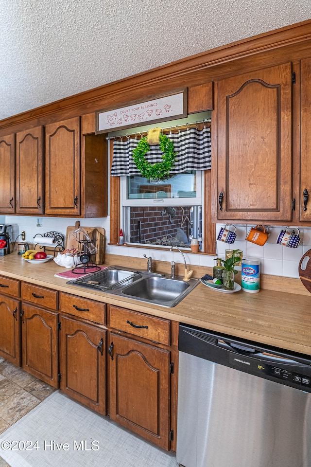 kitchen featuring stainless steel dishwasher, sink, and a textured ceiling