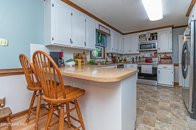 103 Shamrock Rd, Goldsboro, NC 27530 - kitchen featuring appliances with stainless steel finishes, a peninsula, light countertops, a kitchen breakfast bar, and stone finish floors
