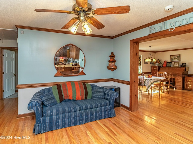 living room featuring light wood-type flooring, a textured ceiling, ceiling fan, and crown molding