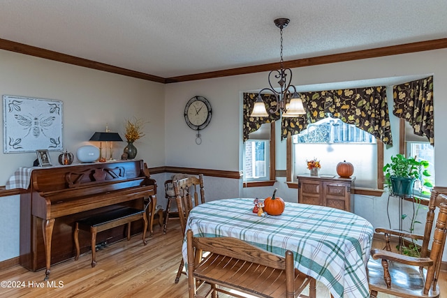 dining space with a textured ceiling, hardwood / wood-style flooring, crown molding, and a notable chandelier