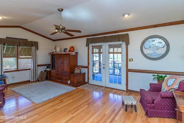 sitting room with ornamental molding, ceiling fan, hardwood / wood-style floors, lofted ceiling, and french doors