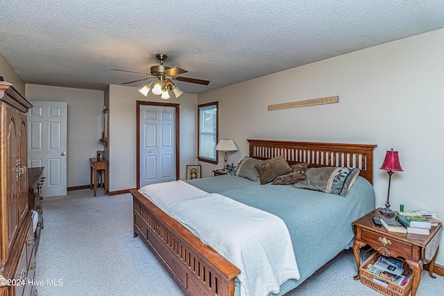 bedroom featuring ceiling fan, light carpet, a closet, and a textured ceiling