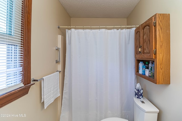 bathroom with a shower with shower curtain, a textured ceiling, and toilet