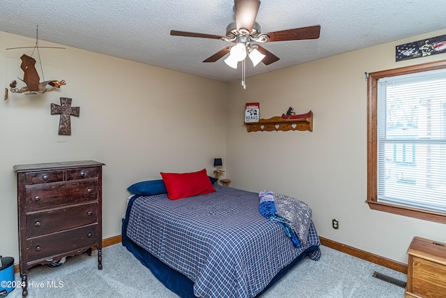 bedroom featuring a textured ceiling, light colored carpet, and ceiling fan