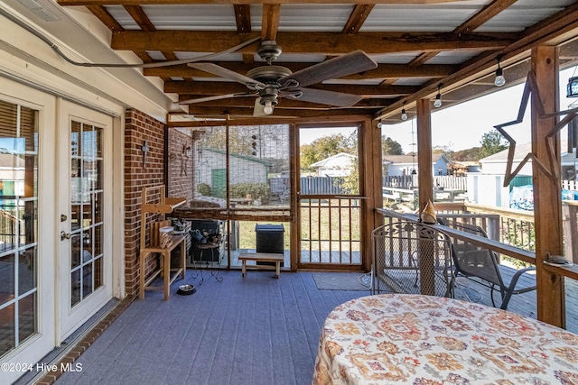 unfurnished sunroom with ceiling fan and beam ceiling