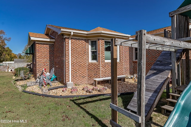 view of side of home featuring a pergola and a yard