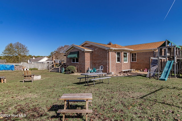 rear view of house featuring a playground and a yard