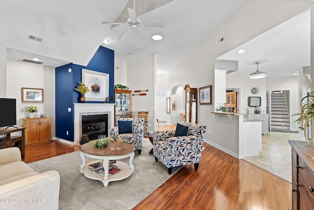 living room with a fireplace, light wood-type flooring, and ceiling fan