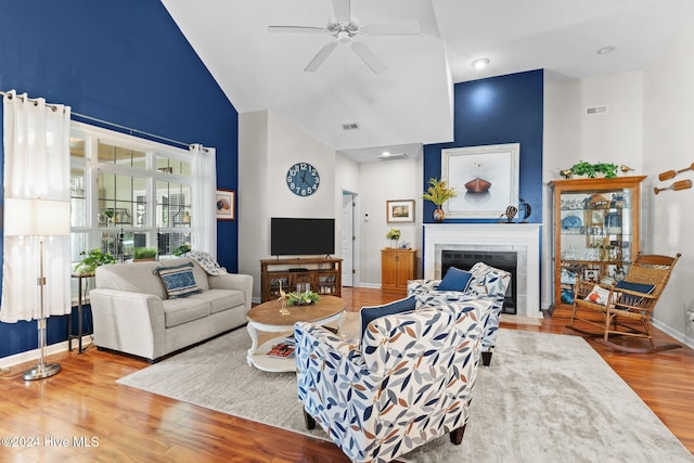 living room featuring a tile fireplace, ceiling fan, hardwood / wood-style floors, and high vaulted ceiling