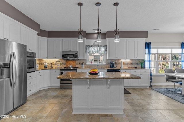 kitchen featuring decorative light fixtures, a wealth of natural light, white cabinetry, and appliances with stainless steel finishes