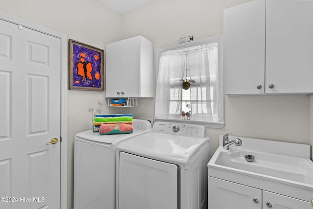 washroom with cabinets, independent washer and dryer, and sink